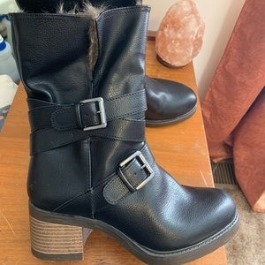 Fur-lined black boots with brown heel and silver buckles